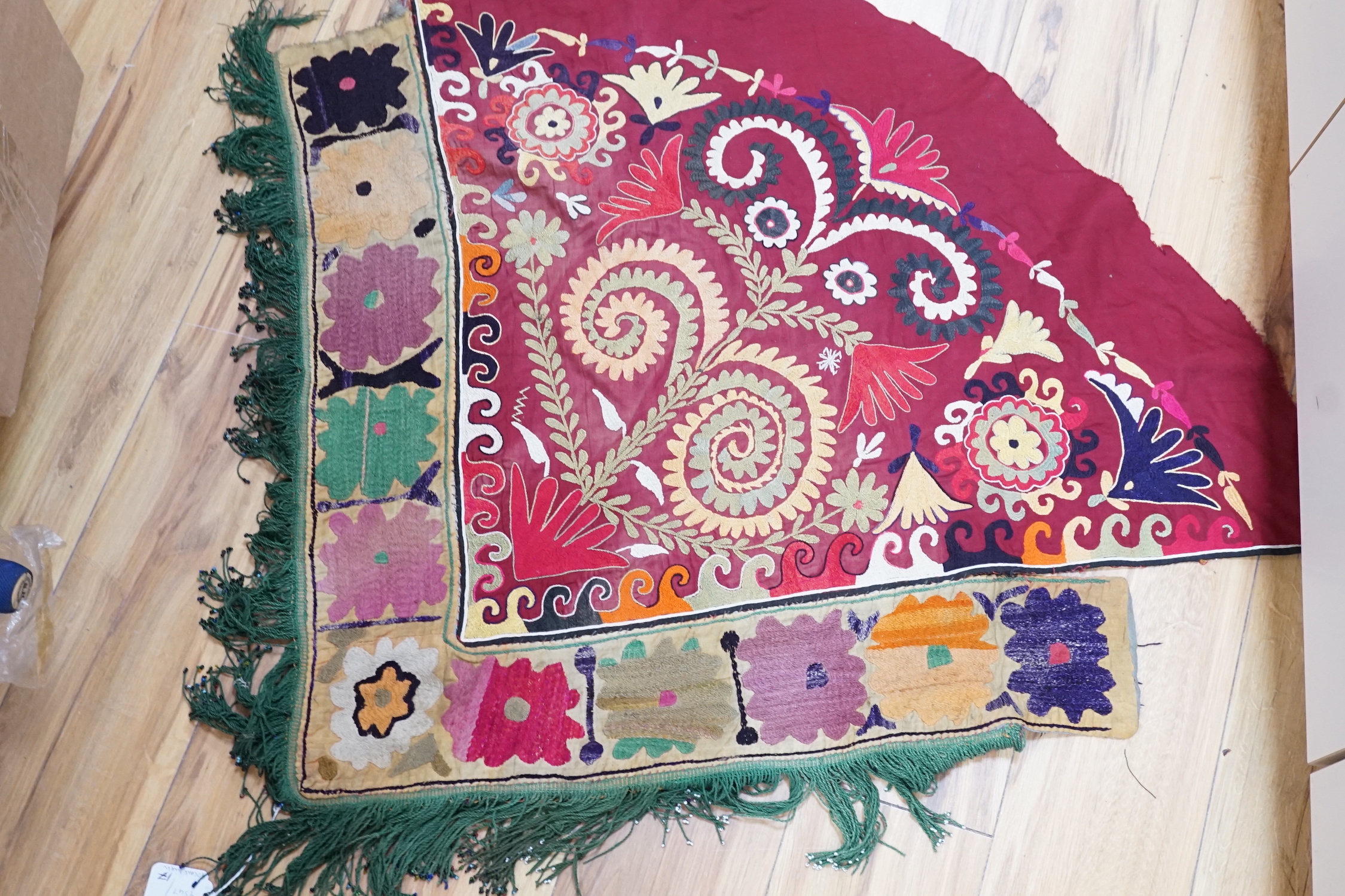 A late 19th/early 20th century Uzbek (Ladak tribe) corner of a multi-coloured embroidered hanging, bordered with green and white beaded fringe, together with a Uzbek border with multi-coloured and white bead fringe and a